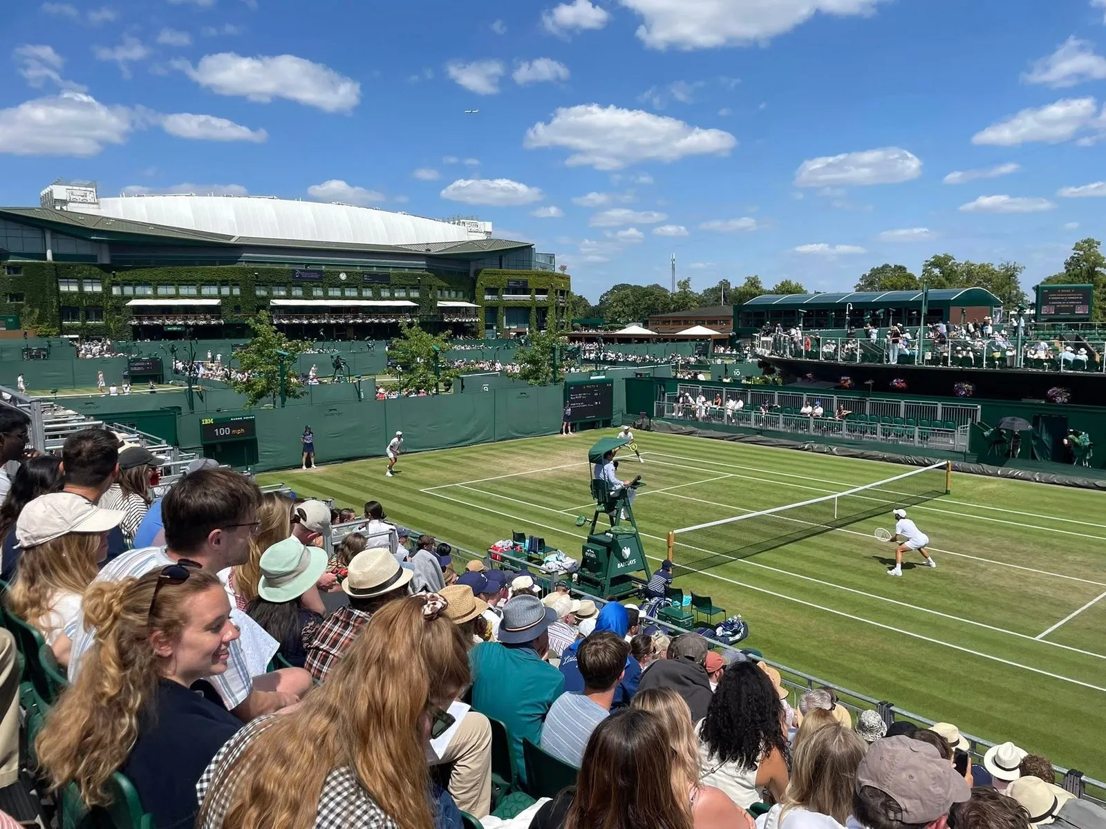 Khán đài đông nghịt người hâm mộ theo dõi một trận đấu đôi nam tại Wimbledon, bất chấp thời tiết nóng bức.