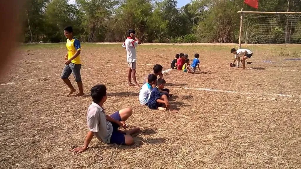 cảnh các cầu thủ đá bóng phủi thời xưa chơi trên sân đất tự nhiên không trang bị chuyên nghiệp