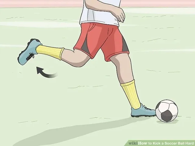 Cầu thủ đang vung chân mạnh mẽ để thực hiện cú sút bóng, tạo ra lực lớn