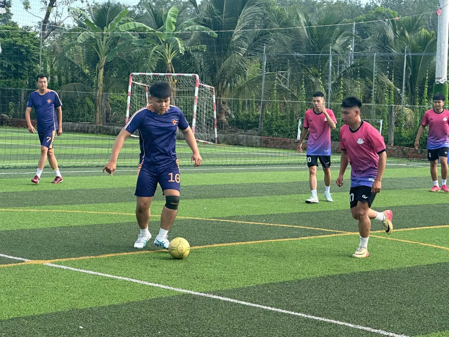 Hai cầu thủ đang tranh bóng quyết liệt trên sân, thể hiện sự cạnh tranh lành mạnh và tinh thần thể thao, như sự tinh tế trong việc chăm chút trang phục bằng bàn là cán bóng mini để luôn hoàn hảo.